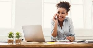 lady smiling on phone in front of laptop